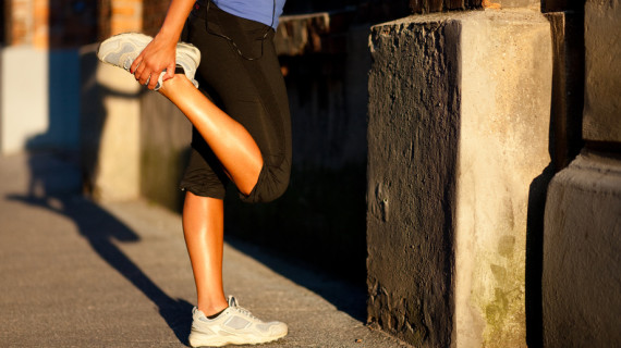 A woman pulling her right foot behind her to stretch while standing