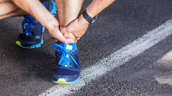 Male runner holding his ankle in pain after a run — highlighting the impact of poor posture on running injuries.