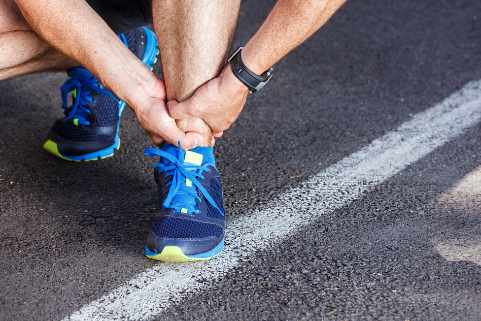 Male runner holding his hurt ankle