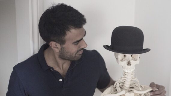Ameet Bhakta, posture specialist in London, standing next to skeleton model at his clinic