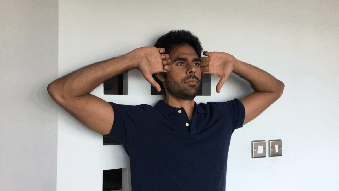 Man doing Standing Elbow Curls posture exercise against a wall to improve shoulder alignment and thoracic posture