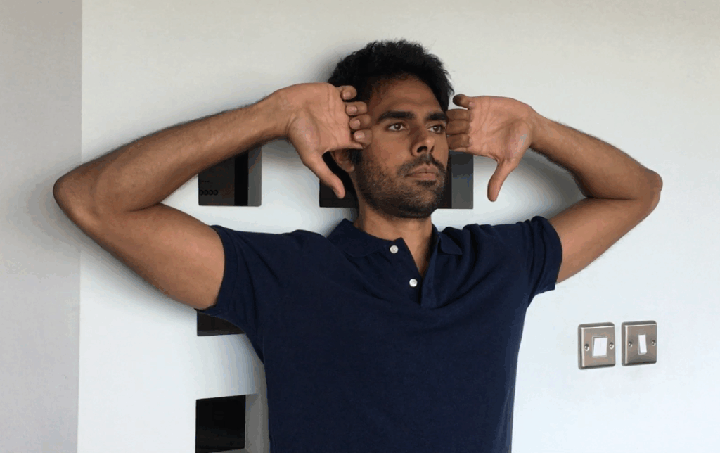 Man doing Standing Elbow Curls posture exercise against a wall to improve shoulder alignment and thoracic posture