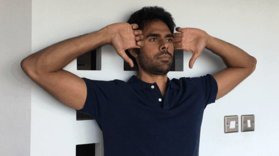 Man doing Standing Elbow Curls posture exercise against a wall to improve shoulder alignment and thoracic posture