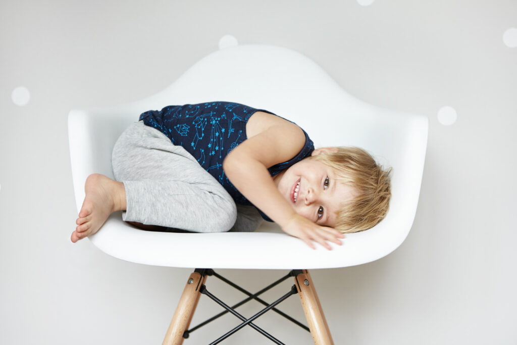 Young child curled up naturally in a chair, showing effortless posture