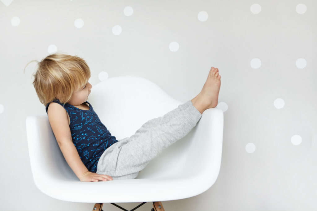 Young child sitting with legs raised, showing relaxed and flexible posture