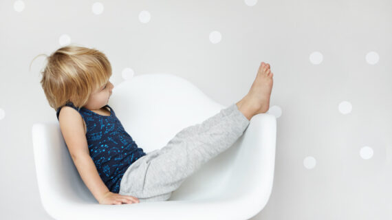 Young child sitting with legs raised, showing relaxed and flexible posture