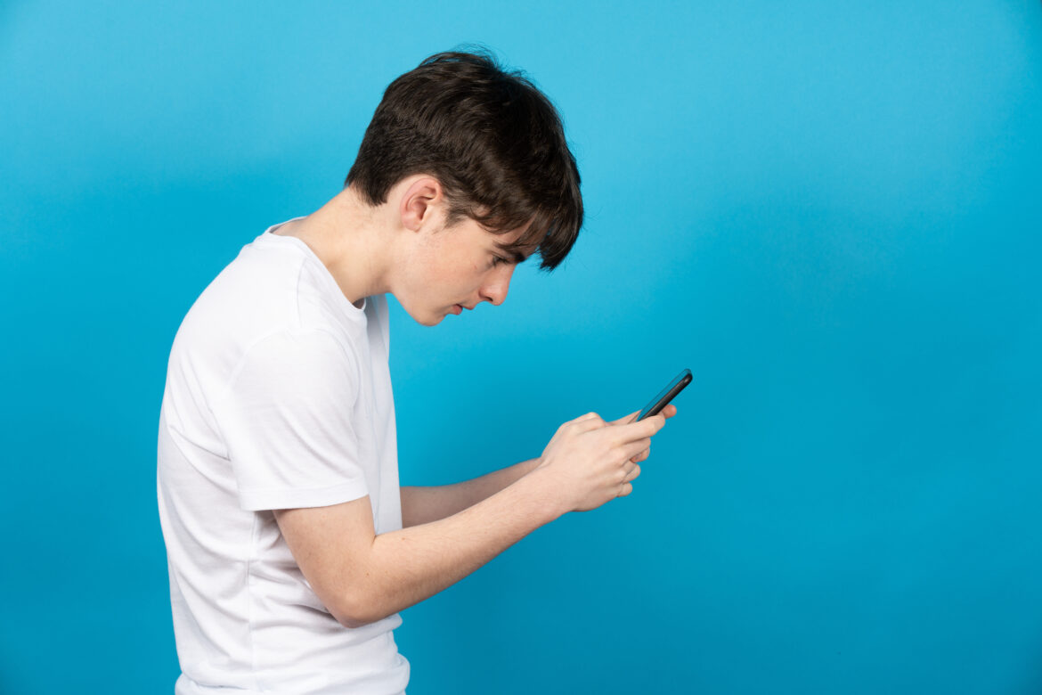 Teenager hunched over smartphone, demonstrating poor posture from extended screen time