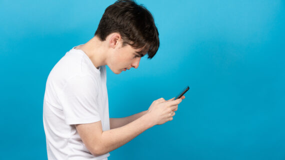 Teenager hunched over smartphone, demonstrating poor posture from extended screen time