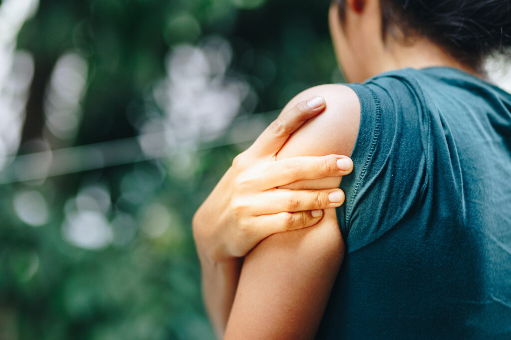 Woman holding her shoulder in pain — highlighting how posture misalignment can contribute to ongoing shoulder issues.
